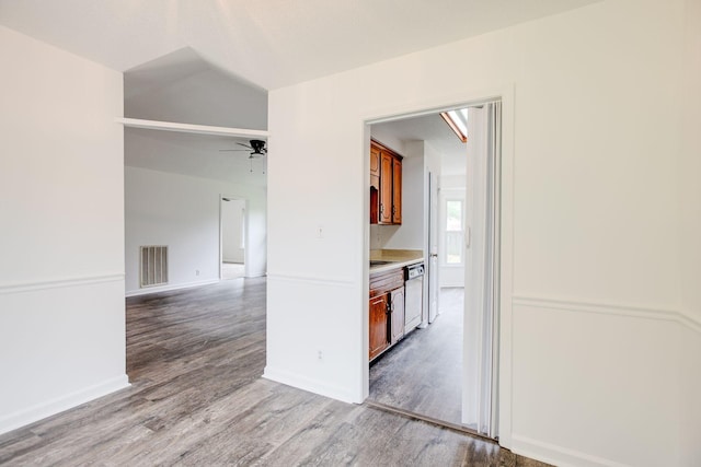 hall with wood finished floors, visible vents, and baseboards