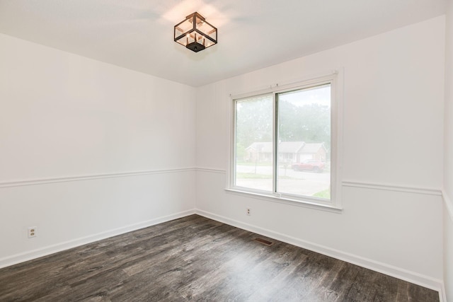 unfurnished room with dark wood finished floors and baseboards