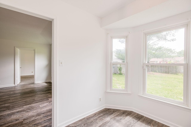 spare room featuring a healthy amount of sunlight, dark wood finished floors, and baseboards