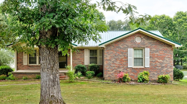 view of front of house with metal roof, brick siding, and a front yard