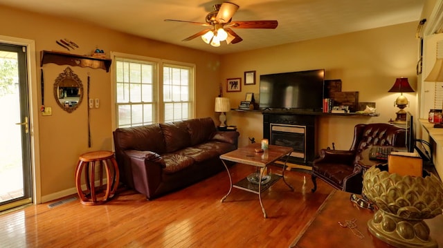 living room with a wealth of natural light, light wood-type flooring, visible vents, and a glass covered fireplace