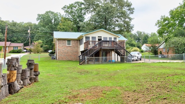 rear view of property featuring stairway, fence private yard, a yard, a wooden deck, and brick siding