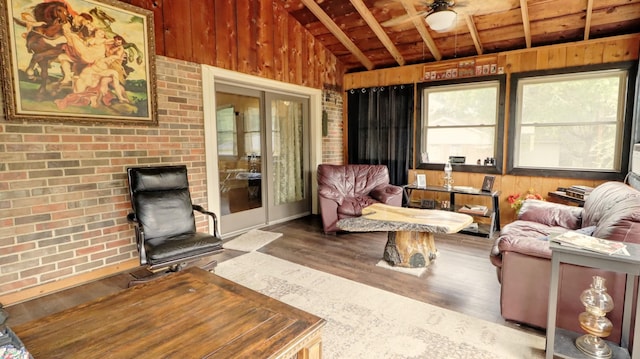 living area featuring wooden walls, lofted ceiling, brick wall, wood ceiling, and wood finished floors