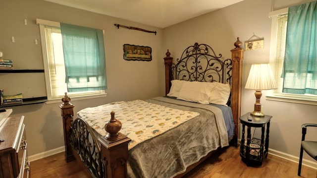 bedroom featuring multiple windows, wood finished floors, and baseboards