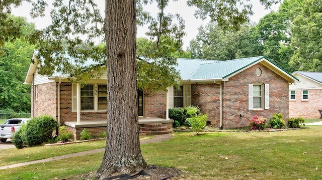 ranch-style house featuring metal roof, a front lawn, and brick siding