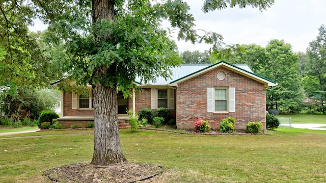 ranch-style home featuring metal roof, brick siding, and a front yard