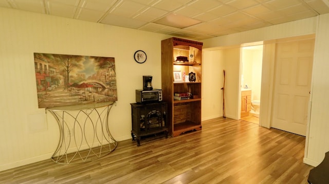 interior space with a wood stove, a paneled ceiling, baseboards, and wood finished floors