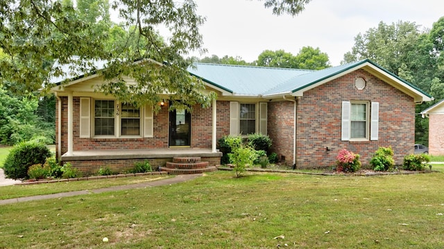 single story home with covered porch, metal roof, a front lawn, and brick siding