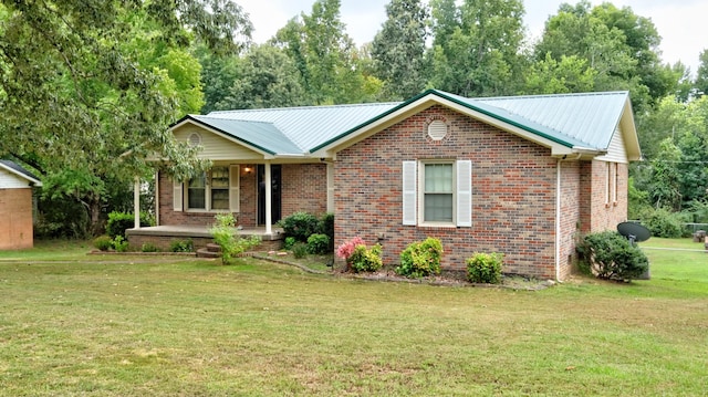 ranch-style home with covered porch, metal roof, brick siding, and a front yard