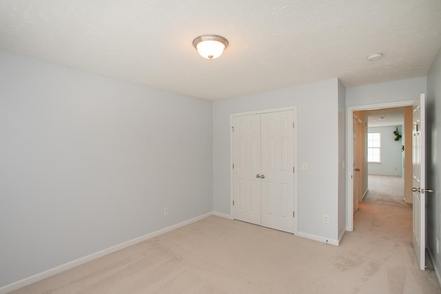 unfurnished bedroom featuring a textured ceiling, light carpet, and a closet