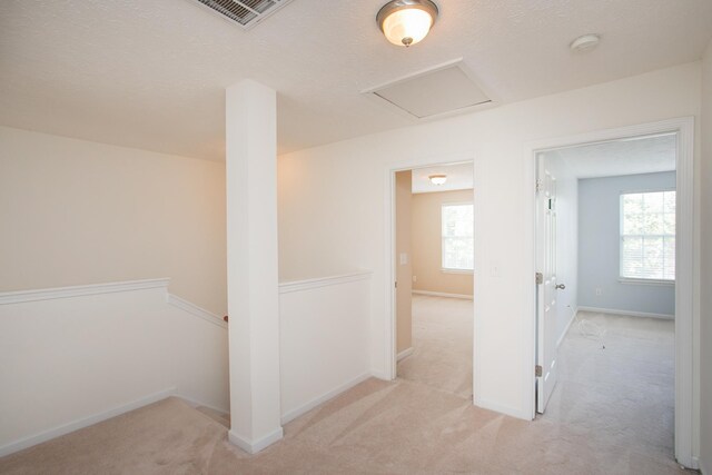 corridor with a textured ceiling and light colored carpet