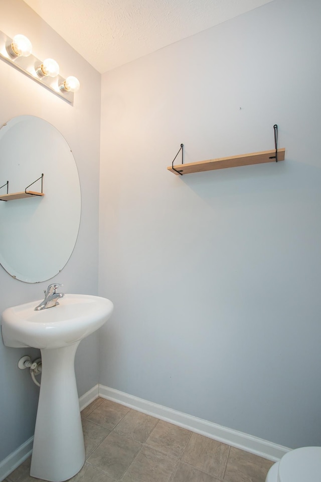 bathroom featuring a textured ceiling, tile patterned floors, and toilet