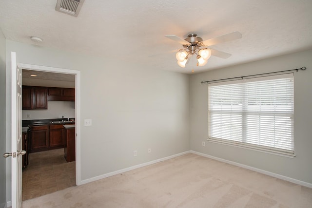 tiled empty room featuring ceiling fan, sink, and a textured ceiling