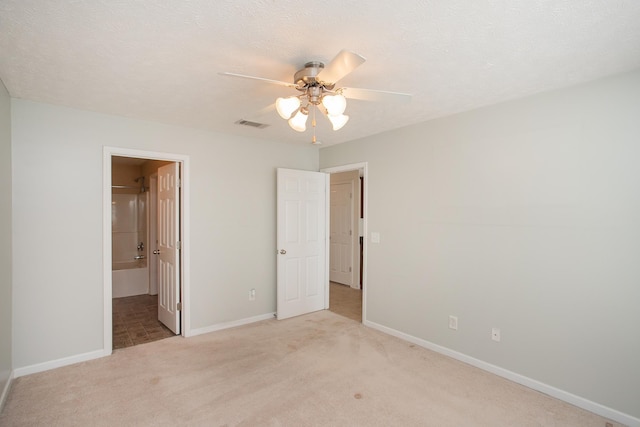 unfurnished bedroom with ceiling fan, connected bathroom, a textured ceiling, and light colored carpet