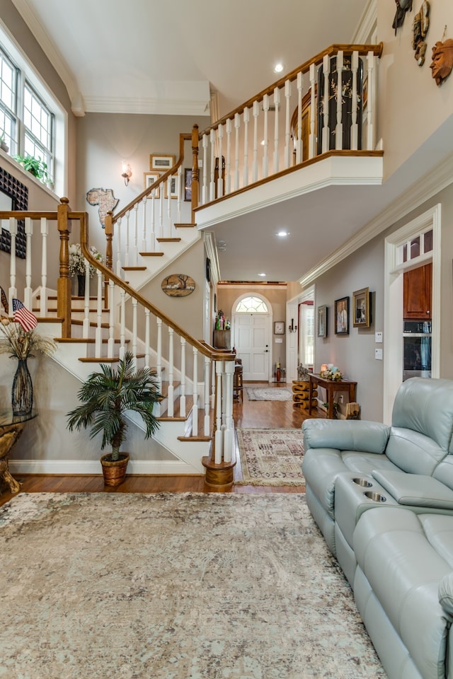 living room featuring crown molding, wood-type flooring, and a towering ceiling