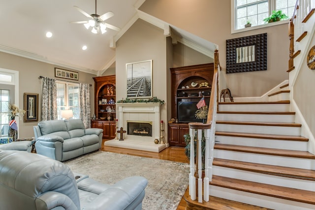 living room with ornamental molding, wood-type flooring, ceiling fan, and high vaulted ceiling