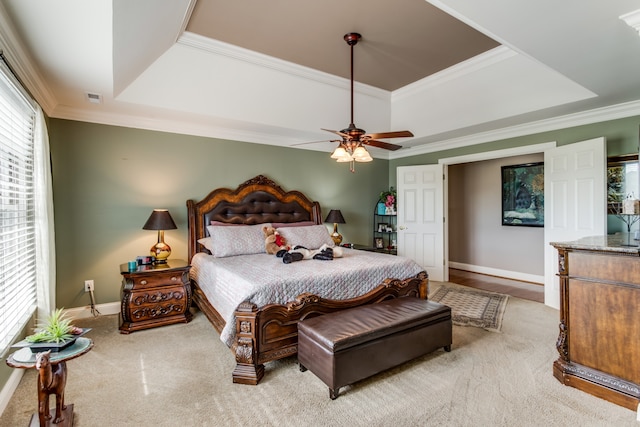 bedroom with ceiling fan, light carpet, crown molding, and a tray ceiling