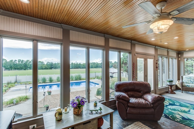 sunroom / solarium featuring a healthy amount of sunlight, wood ceiling, and ceiling fan