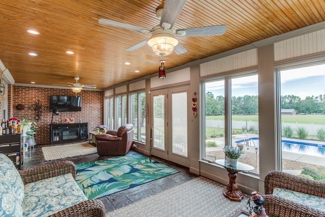 sunroom / solarium with wooden ceiling, a brick fireplace, and ceiling fan