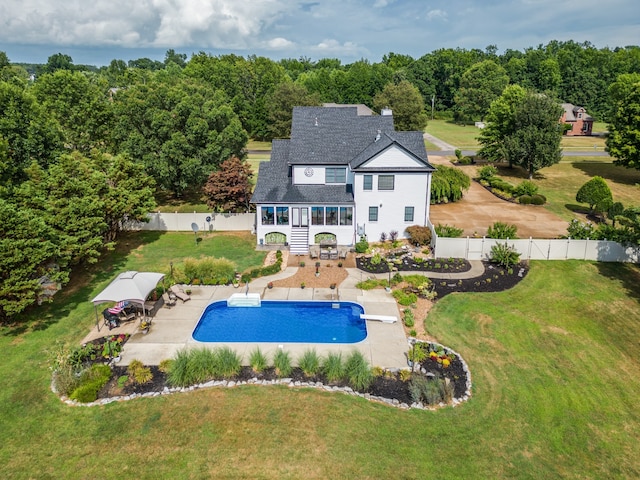 rear view of house featuring a patio area, a yard, and a fenced in pool