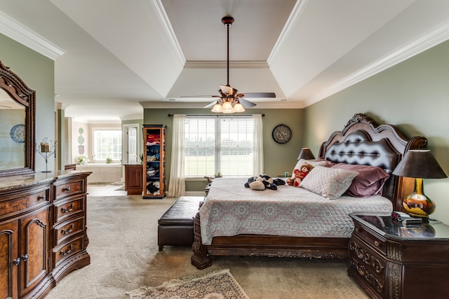 bedroom featuring light carpet, multiple windows, ceiling fan, and a tray ceiling