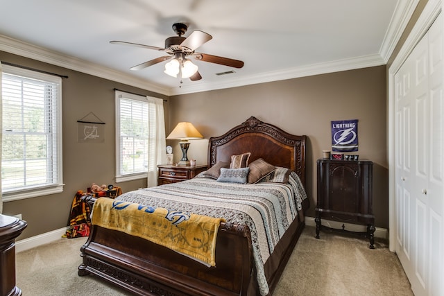 carpeted bedroom with a closet, ceiling fan, and crown molding