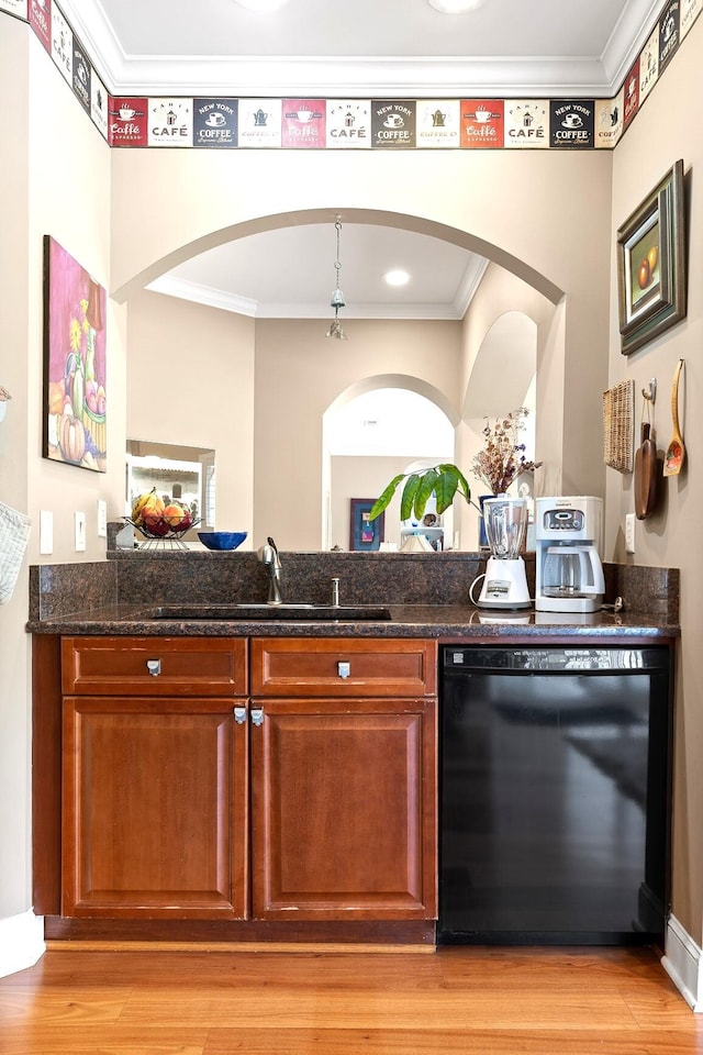 bar featuring dark stone countertops, crown molding, light wood-type flooring, dishwasher, and sink