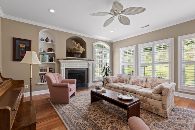 living room with ornamental molding, ceiling fan, hardwood / wood-style floors, and built in shelves