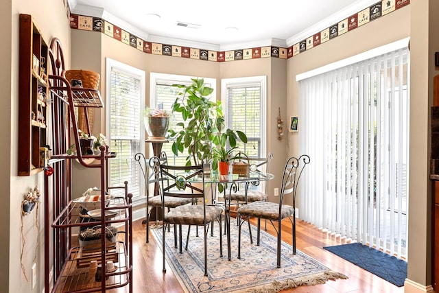 dining space featuring crown molding, hardwood / wood-style flooring, and a healthy amount of sunlight