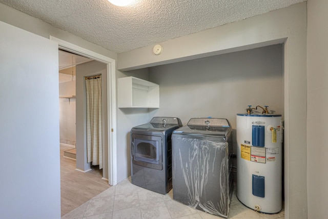 laundry area with a textured ceiling, light tile patterned floors, electric water heater, laundry area, and washing machine and clothes dryer