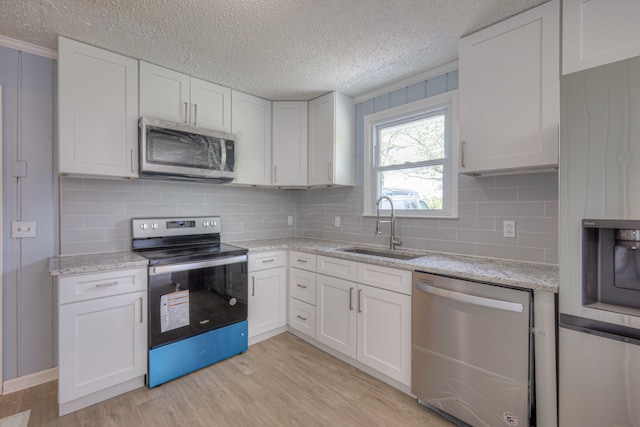 kitchen with white cabinetry, sink, a textured ceiling, appliances with stainless steel finishes, and light wood-type flooring