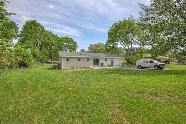 rear view of house with a garage, a yard, and driveway