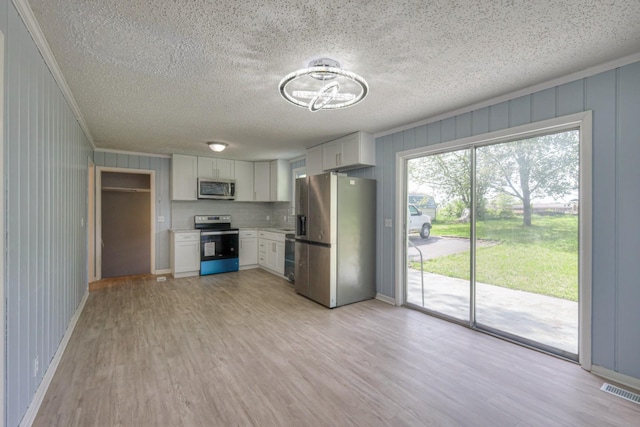 kitchen featuring visible vents, appliances with stainless steel finishes, light wood-style floors, ornamental molding, and white cabinets