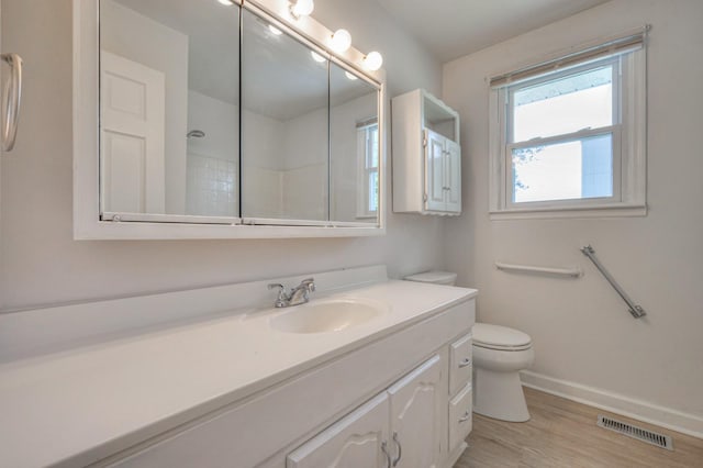 bathroom featuring toilet, vanity, visible vents, baseboards, and walk in shower