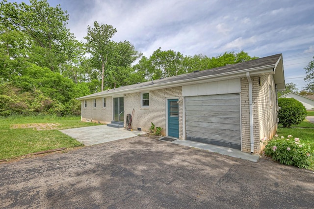 rear view of house featuring entry steps, aphalt driveway, an attached garage, and brick siding