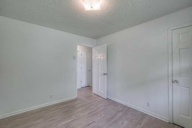 empty room with a textured ceiling, baseboards, and wood finished floors