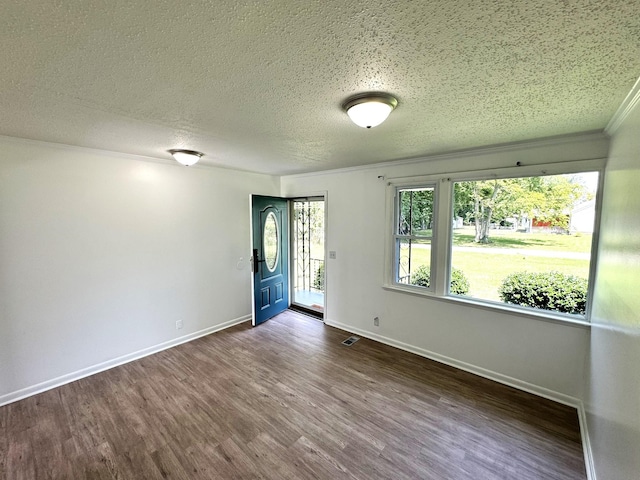 unfurnished room featuring baseboards, visible vents, dark wood finished floors, and a textured ceiling