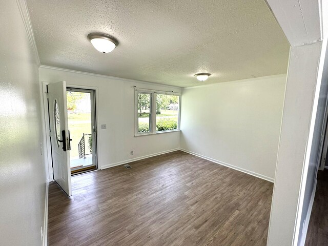 empty room featuring dark wood-type flooring, a textured ceiling, and ornamental molding