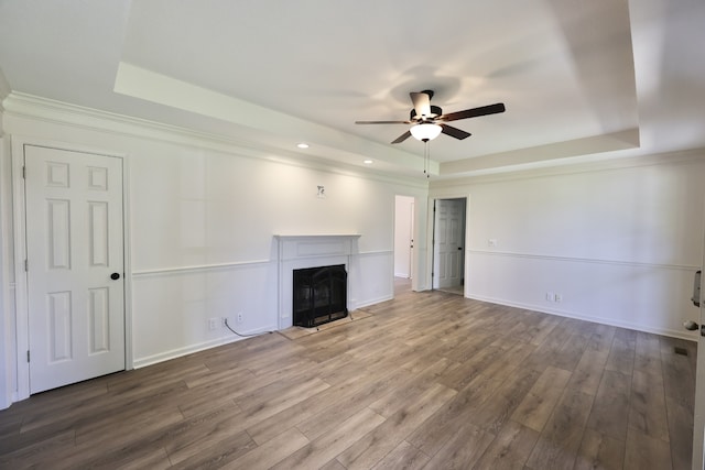 unfurnished living room featuring wood-type flooring, ceiling fan, and a raised ceiling