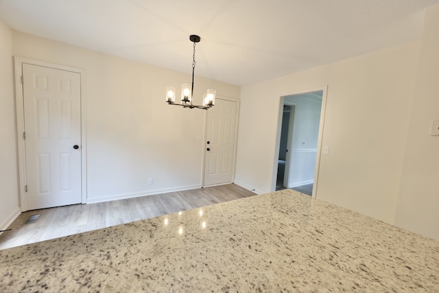 unfurnished dining area with an inviting chandelier and wood-type flooring