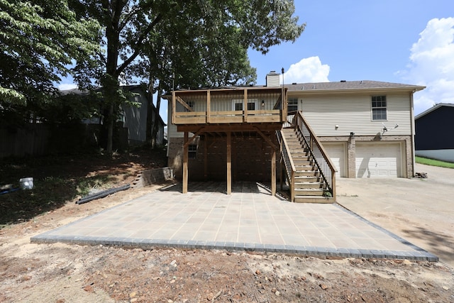 rear view of property with a deck, a garage, and a patio area