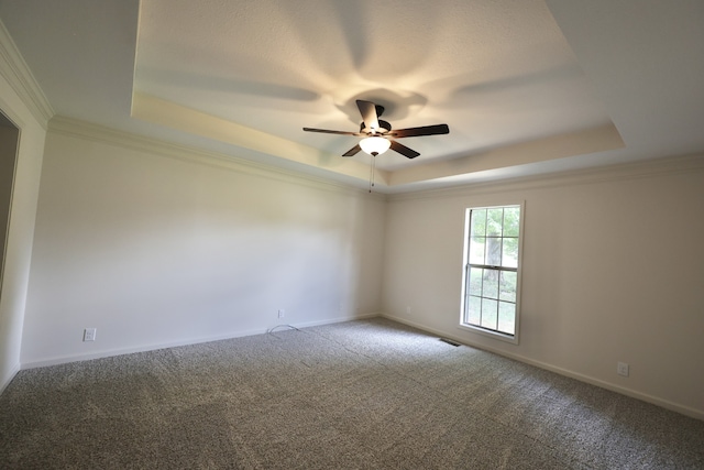 carpeted spare room with ceiling fan, a tray ceiling, and ornamental molding