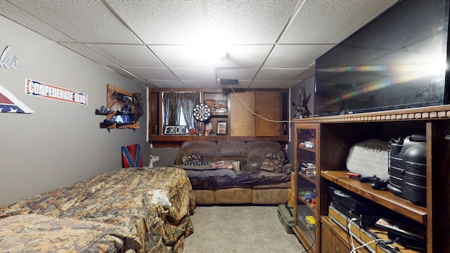 carpeted bedroom featuring a drop ceiling