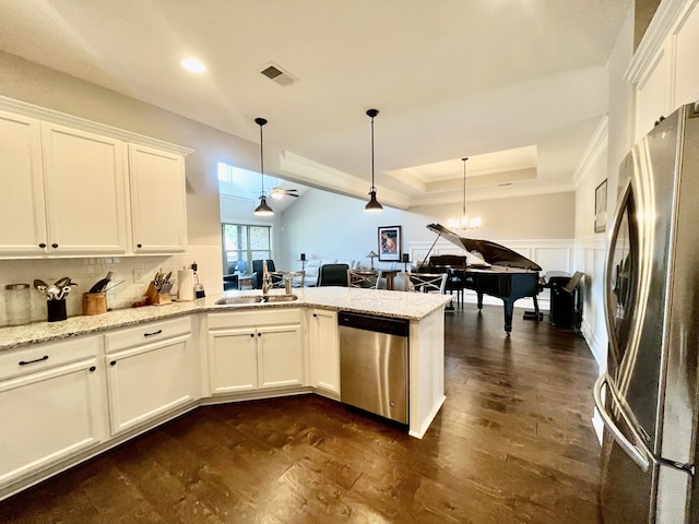 kitchen with appliances with stainless steel finishes, hanging light fixtures, and white cabinets