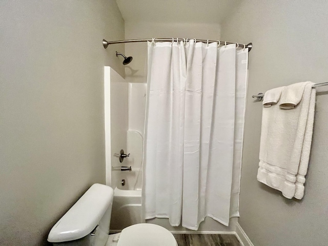 bathroom featuring wood-type flooring, shower / bath combination with curtain, and toilet