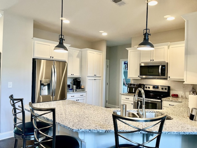 kitchen featuring white cabinetry, a kitchen bar, decorative backsplash, hanging light fixtures, and stainless steel appliances