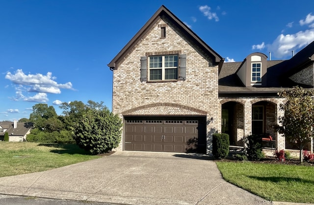 french country home with a garage, brick siding, concrete driveway, a porch, and a front yard