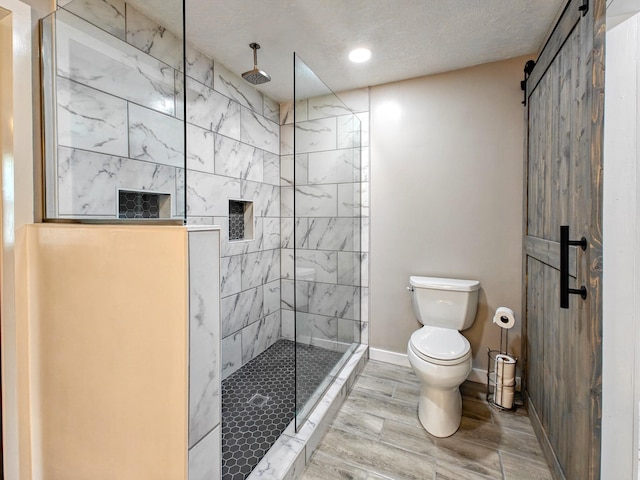 bathroom with toilet, a textured ceiling, and a tile shower