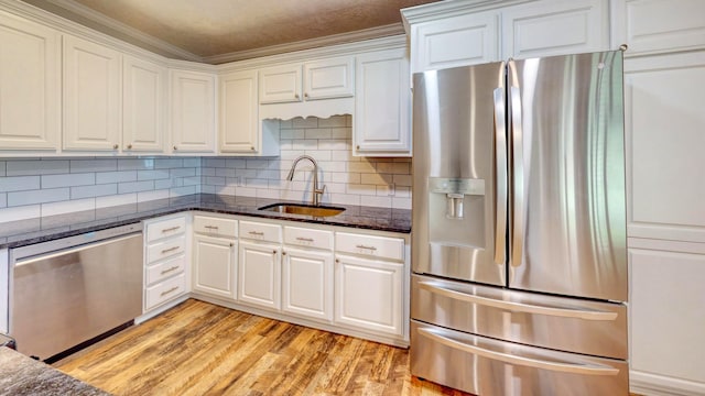 kitchen featuring appliances with stainless steel finishes, sink, dark stone counters, and white cabinets