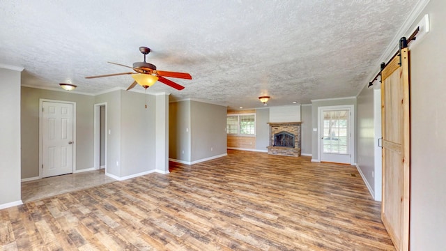 unfurnished living room with ornamental molding, a barn door, and light hardwood / wood-style floors